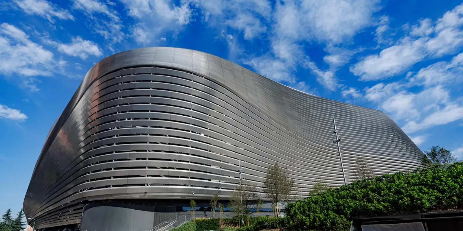 Santiago Bernabéu stadium exterior with its curved steel facade under a blue sky