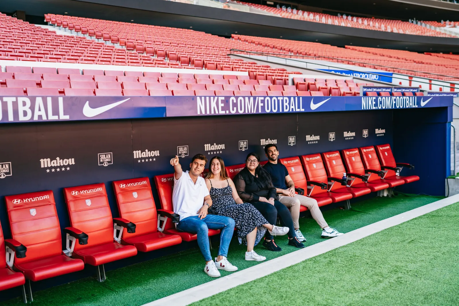 Tour visitors sitting on the red Atlético de Madrid benches