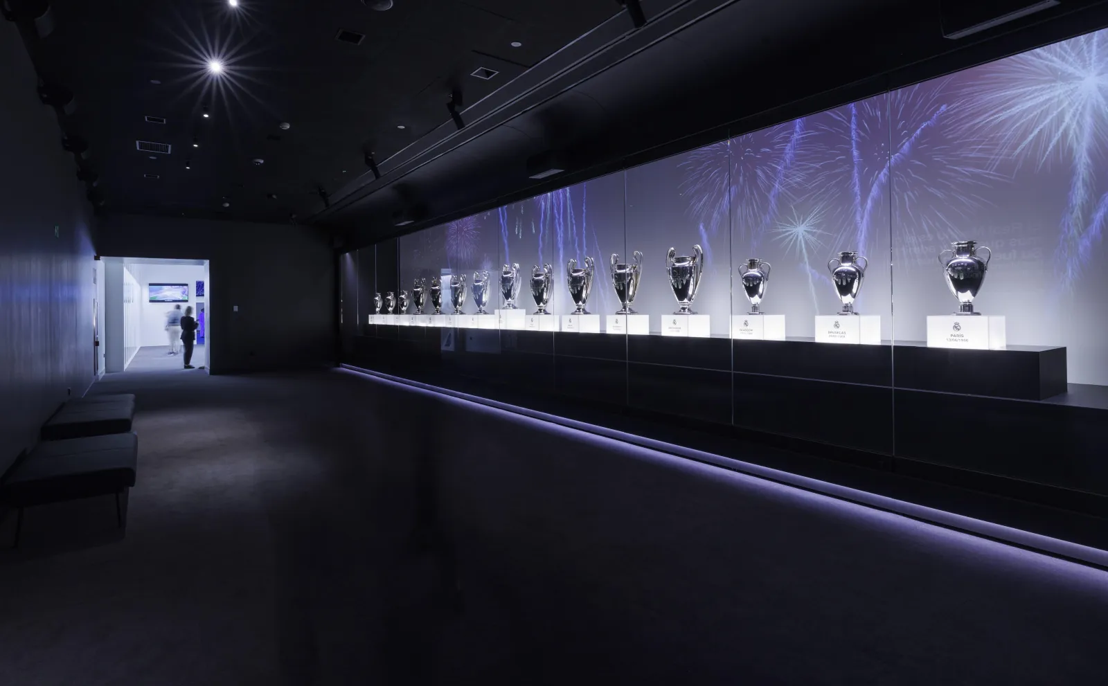 Dimly lit museum corridor lined with Real Madrid trophies